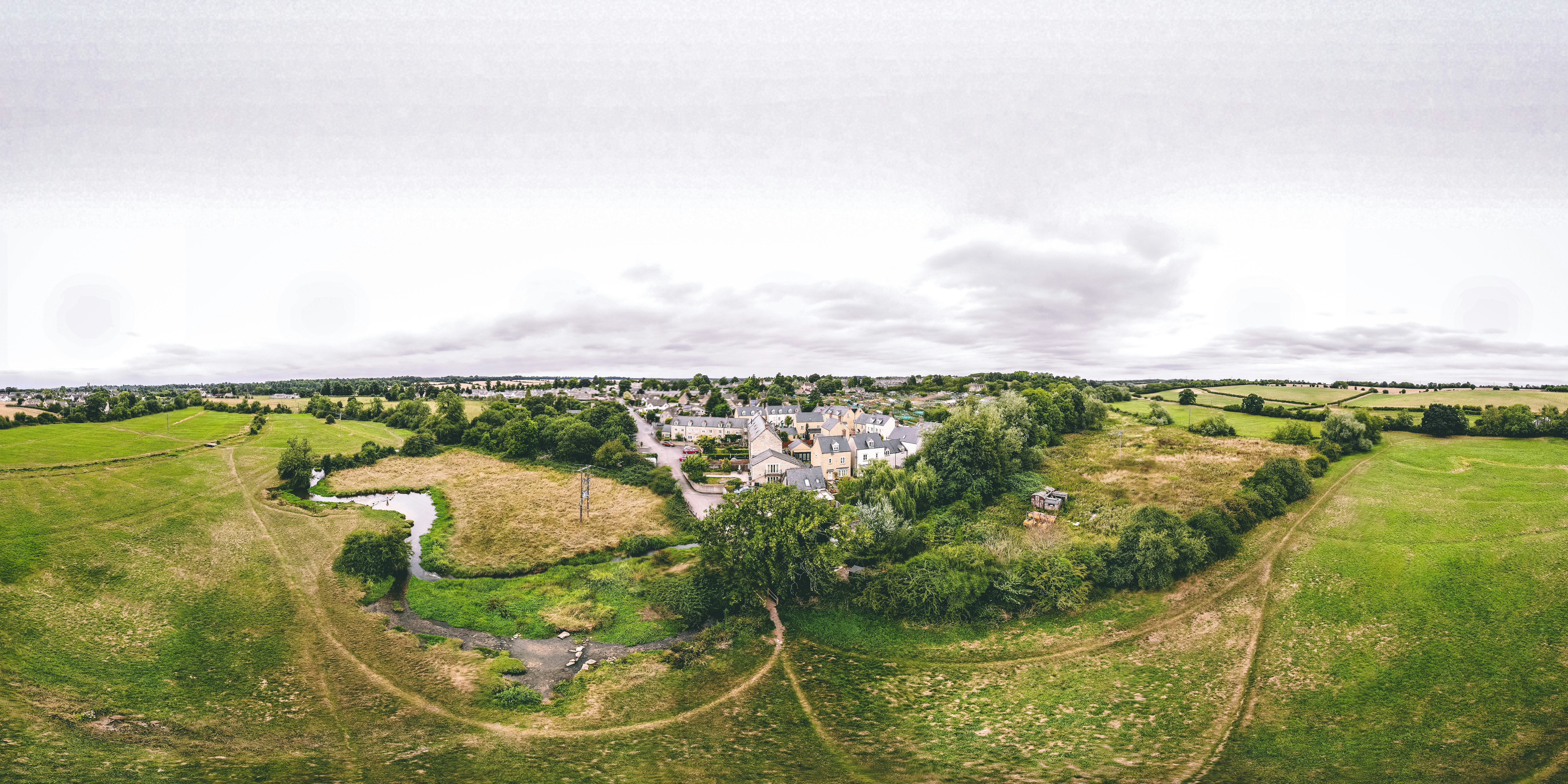 aerial view of green hill and trees under cloudy sky